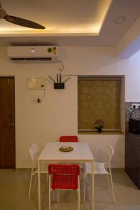 a dining room with a white table and red chairs at ComfyCorner - Luxurious 2-BHK Apartment in Arpora