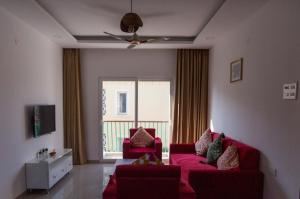 a living room with a red couch and a window at ComfyCorner - Luxurious 2-BHK Apartment in Arpora