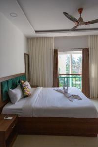 a bedroom with a bed with a ceiling fan and a window at ComfyCorner - Luxurious 2-BHK Apartment in Arpora