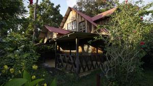 a wooden house with a porch in a garden at Cabañas Toniná Kayab in Ocosingo