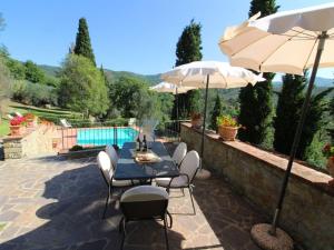 une terrasse avec une table, des chaises et des parasols dans l'établissement Belvilla by OYO Borgo Caprile, à Castiglion Fiorentino