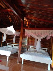 two beds in a room with wooden ceilings at FOREST BREATH ECO-LODGE in Tân Phú