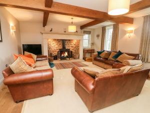 a living room with leather furniture and a fireplace at Anneside in Carnforth