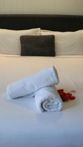 a white towel laying on top of a white bed at Dandaloo Gardens in Arcadia