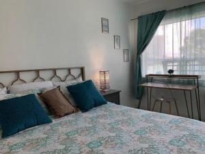 Un dormitorio con una cama con almohadas azules y una ventana en International Inn on the Bay, en Miami Beach