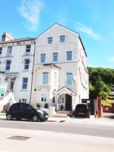 un edificio blanco con dos coches estacionados frente a él en The Norman Guest House en Dover