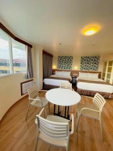 レガスピにあるHotel Sentro Legazpiのベッド2台、テーブルと椅子が備わるホテルルームです。
