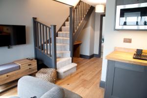 a living room with a staircase with a tv and a couch at Little Elm - luxury home from home, free parking, 30-40 mins walk from Bath city centre in Bath