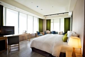 台東市にあるザ スイート 台東の大型ベッドとテレビが備わるホテルルームです。