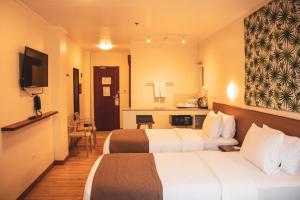 a hotel room with two beds and a television at Hotel Sentro Legazpi in Legazpi
