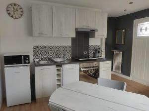 a kitchen with white cabinets and a clock on the wall at Belle dépendance, appartement cosy, tout confort in Montpellier