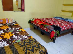 um quarto com duas camas e uma cama com um cobertor em Sudhaahomestay em Hampi