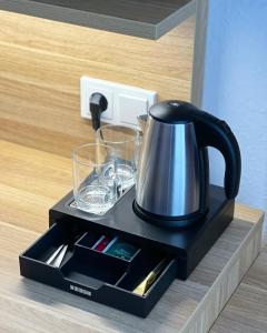 a tea kettle and glasses on a black tray at Hotel Well Garni in Wittlich