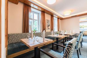 een restaurant met houten tafels, stoelen en ramen bij Hotel Markgraf in Lehnin