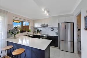 a kitchen with a white counter top and a refrigerator at Spacious 2BR near The Entrance Beach - 7Min Walk! in The Entrance