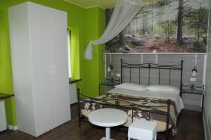 ein Schlafzimmer mit grünen Wänden, einem Bett und einem Tisch in der Unterkunft Albergo Garni Barancio in Auronzo di Cadore