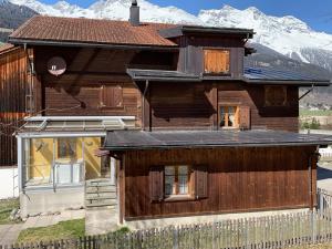 a large wooden house with mountains in the background at Casa Steilalva - grosszügiges Chalet für erholsamen Familienurlaub in Surrein