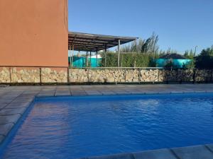 einem Pool vor einem Gebäude mit einer Steinmauer in der Unterkunft Cabañas Doña Irma in San Rafael