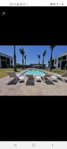 una piscina con bancos, una mesa y una piscina en lovely 1 bedroom apartment en Ballito