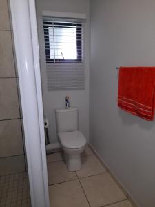 a bathroom with a toilet and a window and a red towel at lovely 1 bedroom apartment in Ballito