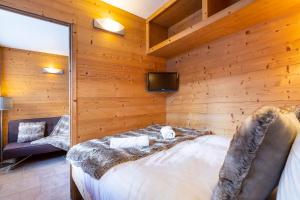 ヴァル・トランスにあるVal Thorens-Cosy Lauzières 415の木製の壁のベッドルーム(ベッド1台、テレビ付)