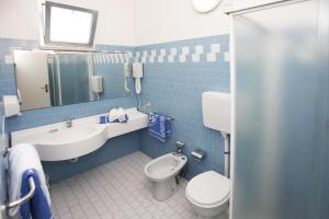 bagno piastrellato blu con servizi igienici e lavandino di Hotel Villa dei Fiori - sul mare con piscina a Rimini