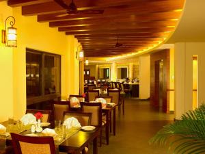 een restaurant met houten plafonds en tafels en stoelen bij Poetree Thekkady in Thekkady