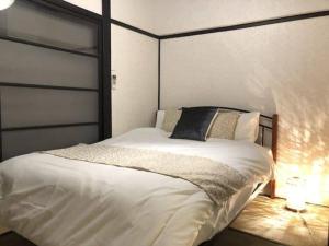 a bedroom with a white bed with a black headboard at ゲストハウス扇 in Takamatsu