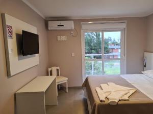 1 dormitorio con 1 cama, TV y ventana en Hotel Jardim do Mar, en Torres