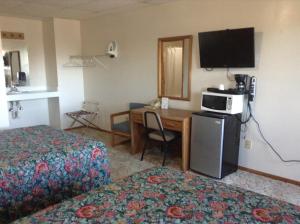 a hotel room with a bed and a desk with a television at Downtown Motel in Gaylord