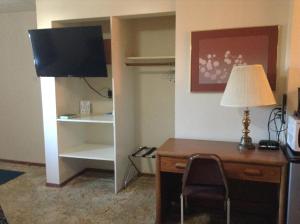 Cette chambre comprend un bureau avec une lampe et une armoire. dans l'établissement Downtown Motel, à Gaylord