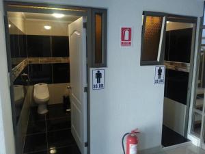 a bathroom with a toilet and a door with signs at Hotel Portal del Norte in Copiapó +39 photos