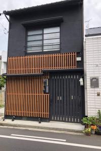 Maison noire et brune avec un portail en bois dans l'établissement ゲストハウス扇, à Takamatsu