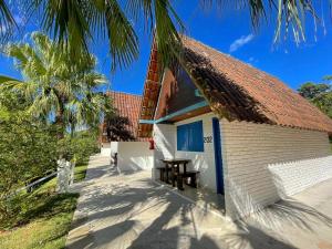 a white building with a table and a palm tree at Tijota Hotel Fazenda in Ipatinga