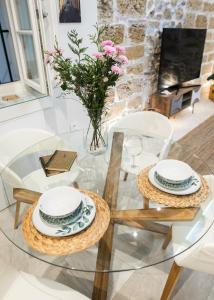een glazen tafel met 2 stoelen en een vaas met bloemen bij innCádizCASA SEÑORIAL DE 1790 in Cádiz +24 foto's