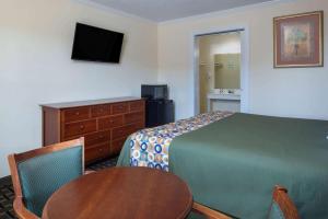 a hotel room with a bed and a table and a desk at Travelodge by Wyndham Orangeburg in Orangeburg