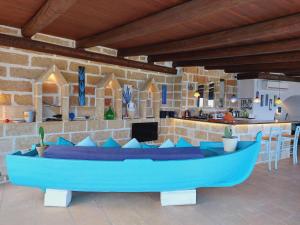 VILLE GIRASOLI "VILLA NELLA BAIA" with PRIVATE SWIMMING POOL في تريكاس: غرفة معيشة مع أريكة زرقاء وبار
