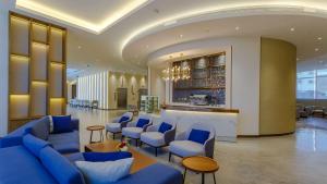 a lobby with blue chairs and a bar at Clarion Hotel Jeddah Airport in Jeddah