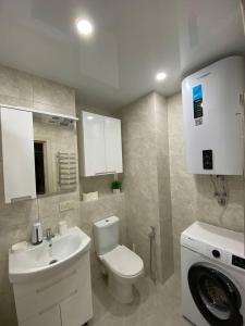 a bathroom with a toilet and a sink and a washing machine at Замечательная евродвушка район Теремков 209 in Teremki +9 photos