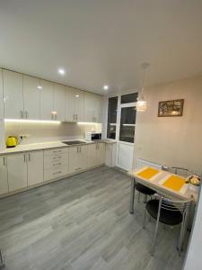 a large kitchen with white cabinets and a table at Замечательная евродвушка район Теремков 209 in Teremki