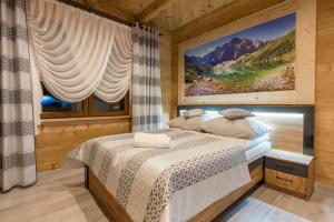 a bedroom with a bed and a large painting on the wall at Apartamenty Chłabówka in Zakopane