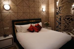 a bedroom with a white bed with two red pillows at Hôtel Volubilis Meknès in Meknès