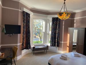 a bedroom with a bed and a window and a chandelier at The Elizabeth House Hotel in Southampton