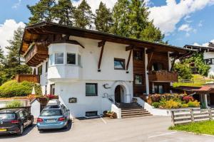 una casa con dos coches aparcados en un estacionamiento en Appartement Rianne/Landhaus Almidyll, en Seefeld in Tirol