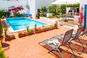 una piscina con sillas, una mesa y una sombrilla en Villa Marrakech by Algarve Vacation, en Carvoeiro