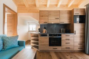 a kitchen with wooden cabinets and a blue couch at S'Kathrina - Appartements in Schattwald