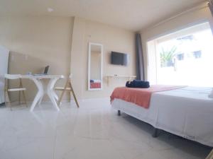 a bedroom with a bed and a desk with a laptop at Flats Taiba Praia Centro in Taíba