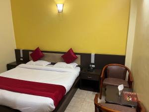 una habitación de hotel con 2 camas y una silla en Hotel Magnet House, en Dehradun