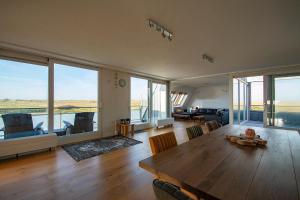 sala de estar amplia con mesa de madera y ventanas grandes. en Penthouse Duinerei- Groote Keeten, en Callantsoog