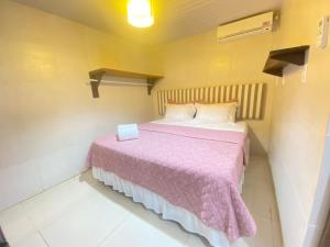a small bedroom with a bed with a pink blanket at FLAT BAÍA DO SANCHO in Fernando de Noronha